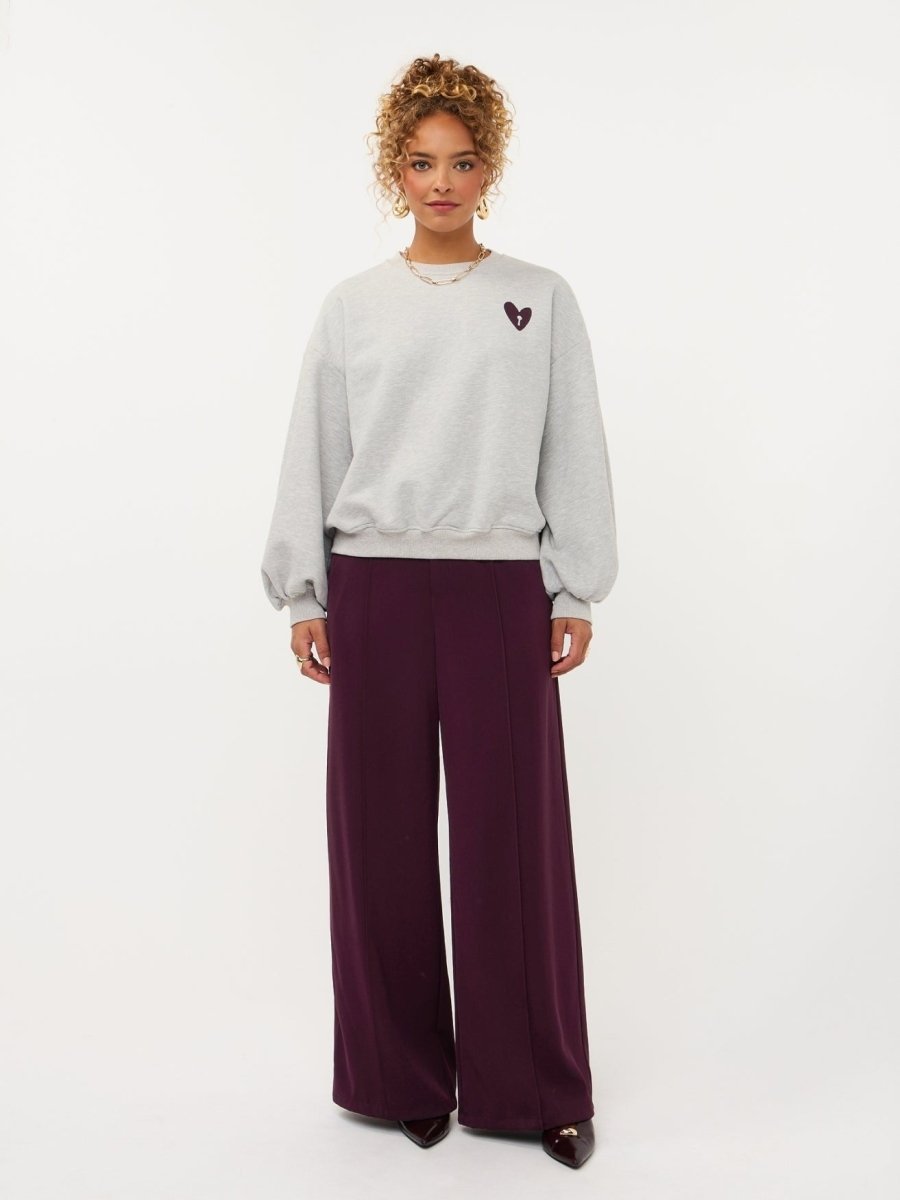 Model in grijze sweater met hartje en print op de rug Ydence Checked In | Jo&Co Club