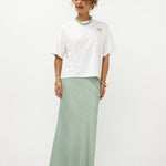 Model in oversized off-white Ydence Sunday mornings T-shirt met sage groene satijnen rok | Jo&Co Club