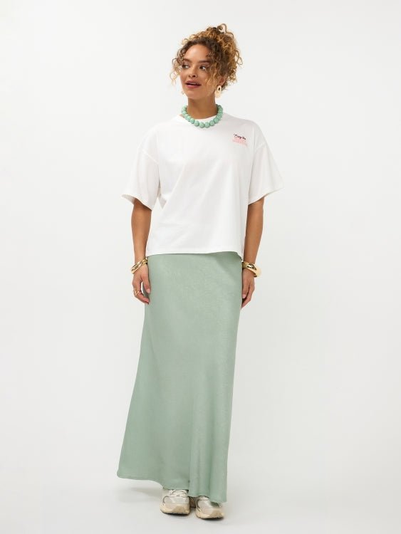 Model in oversized off-white Ydence Sunday mornings T-shirt met sage groene satijnen rok | Jo&Co Club