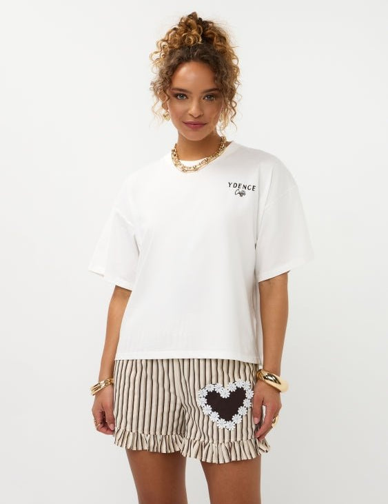 Model in oversized off-white Ydence Caffè T-shirt met gestreepte ruche-short, frontaal | Jo&Co Club