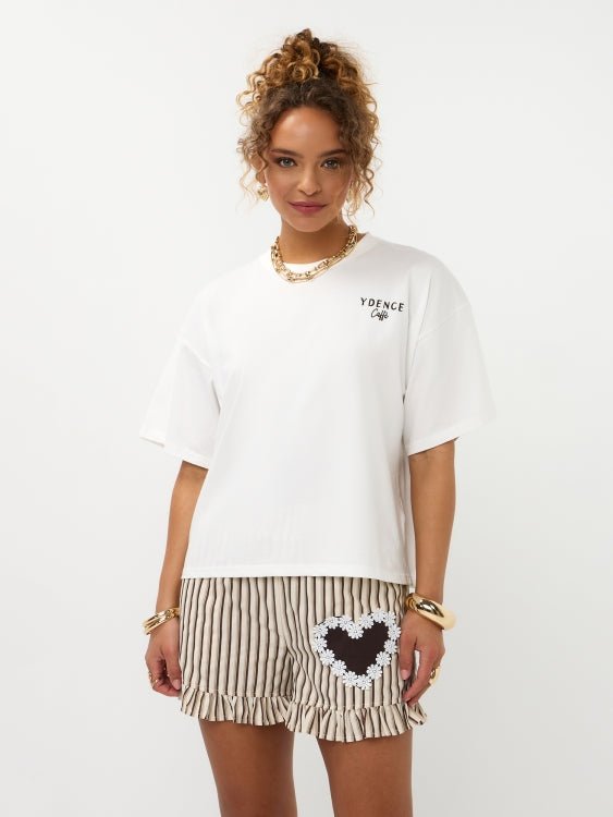 Model in oversized off-white Ydence Caffè T-shirt met gestreepte ruche-short, frontaal | Jo&Co Club