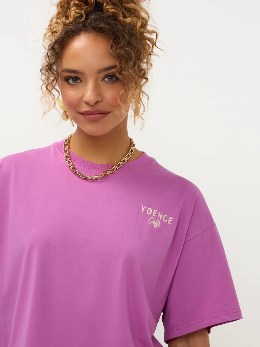 Een close-up portret van een model met krullend, opgestoken haar, die een paars T-shirt met een | Ydence cafe | Jo&Co Club