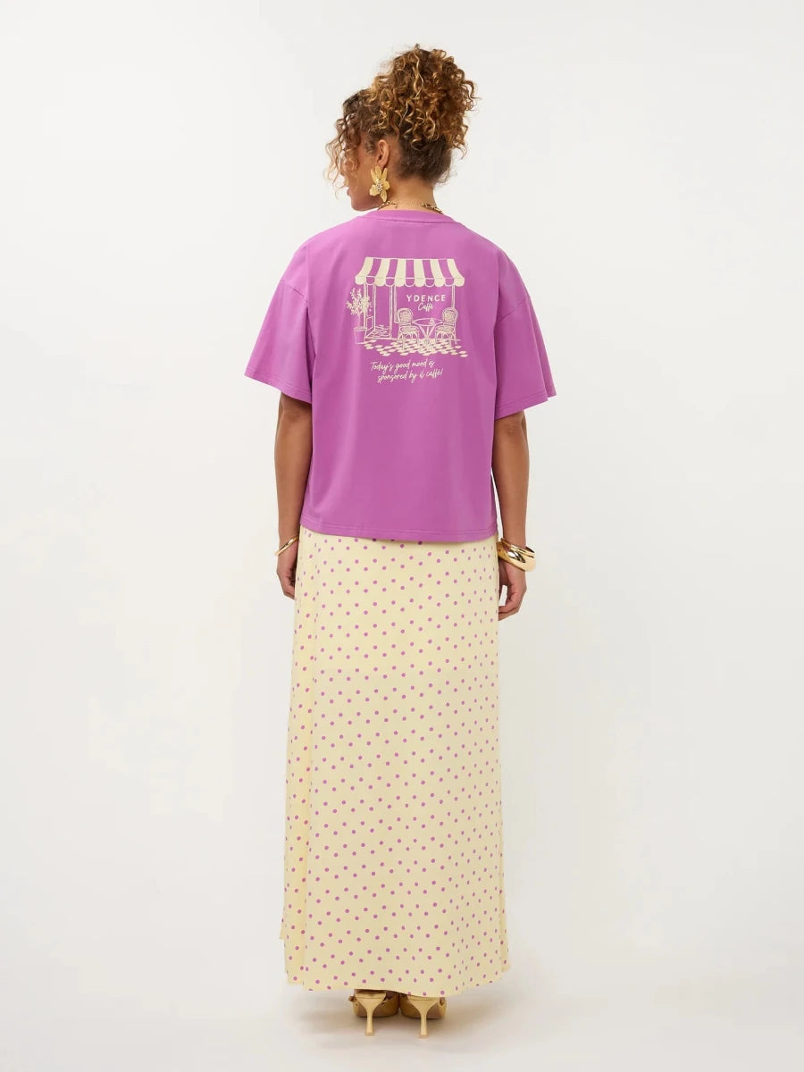 Een model, van achteren gefotografeerd, draagt een oversized paars T-shirt met korte mouwen | Ydence cafe | Jo&Co Club