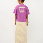 Een model, van achteren gefotografeerd, draagt een oversized paars T-shirt met korte mouwen | Ydence cafe | Jo&Co Club