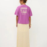 Een model, van achteren gefotografeerd, draagt een oversized paars T-shirt met korte mouwen | Ydence cafe | Jo&Co Club