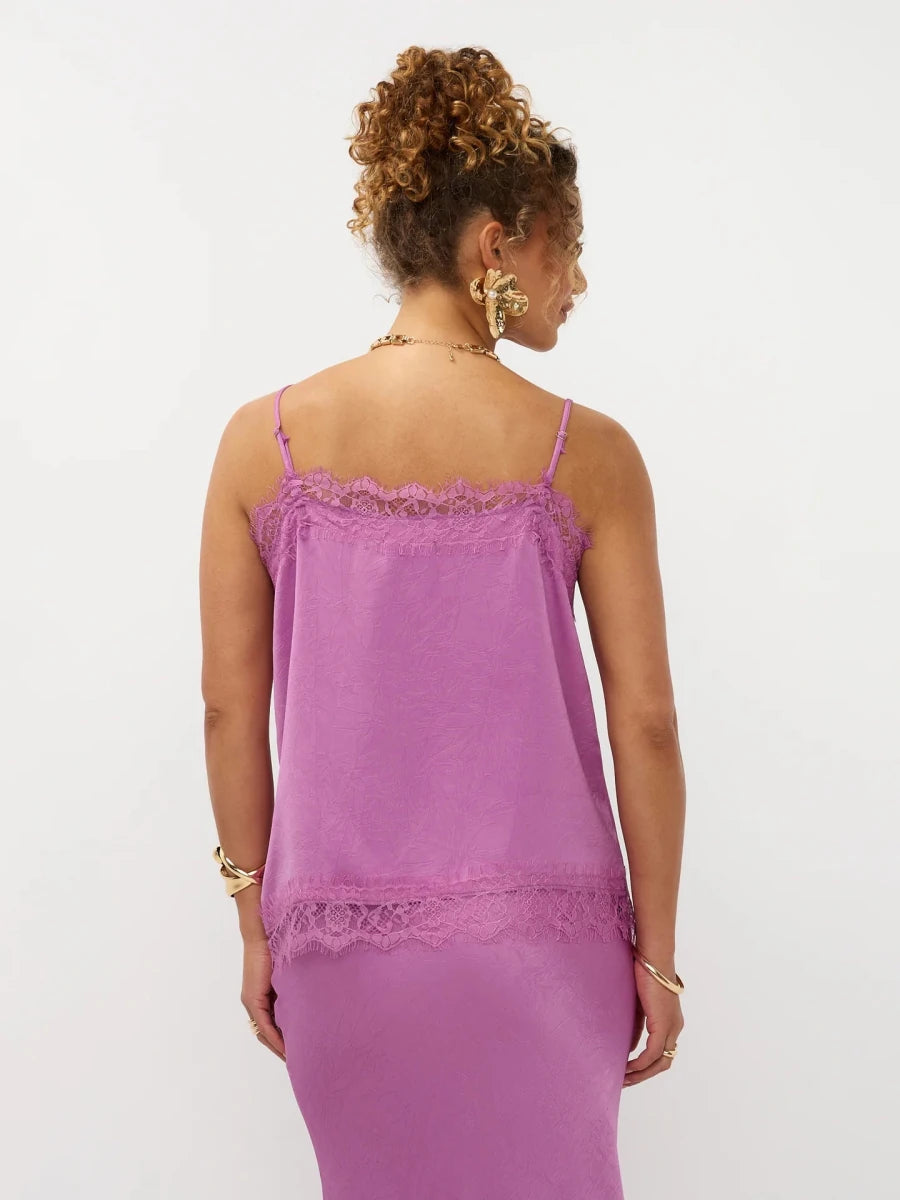 Een model, van achteren gefotografeerd, draagt een lila camisole top met dunne spaghettibandjes | Ydence Callie | Jo&Co Club