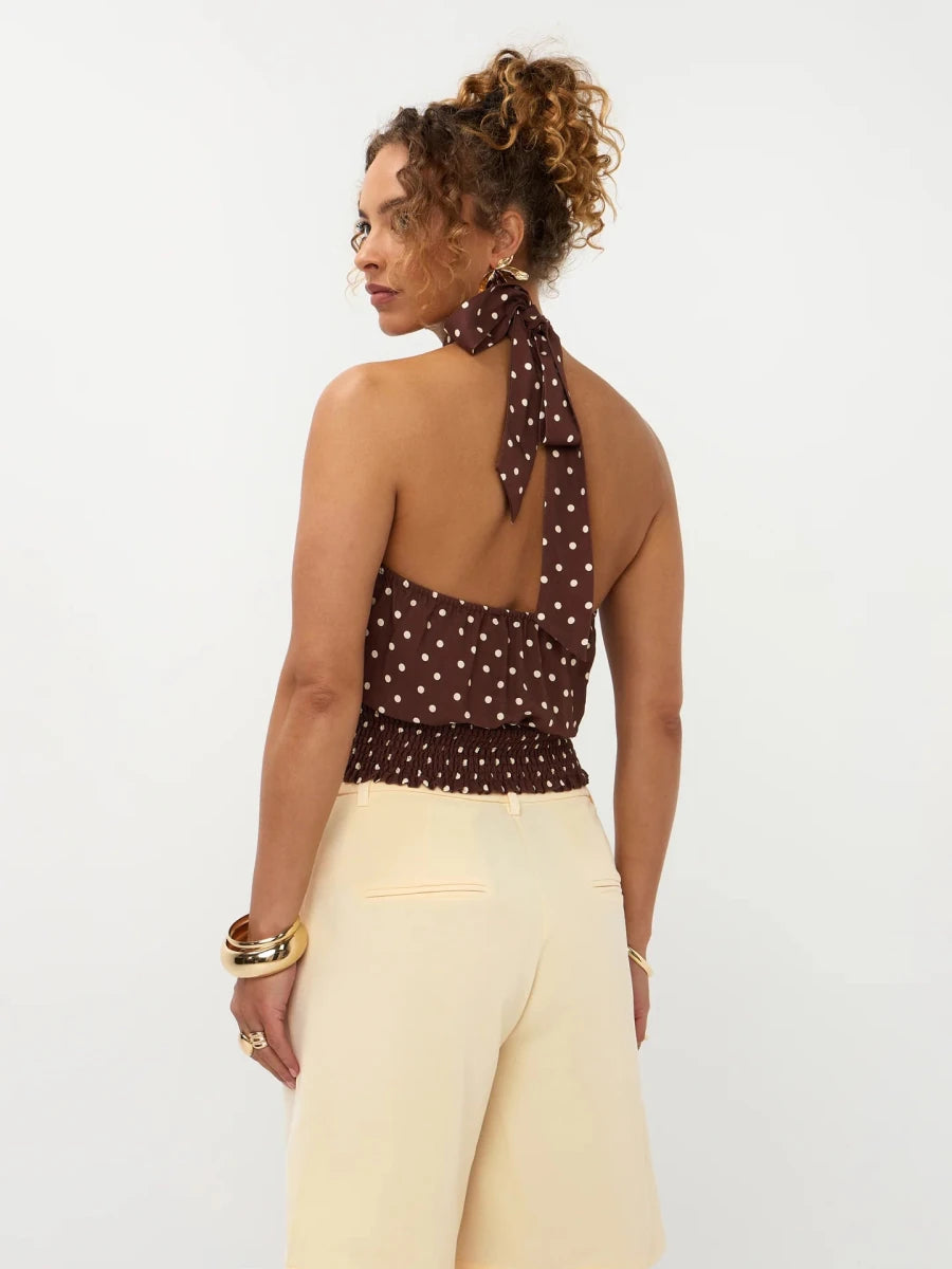 Een model, van achteren gefotografeerd, draagt een bruine haltertop met een witte polkadotprint | Ydence Jamie | Jo&Co Club