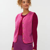 Model draagt het puck gilet van ydende van teddy stof in de kleur fuchsia over de knitted top devina.