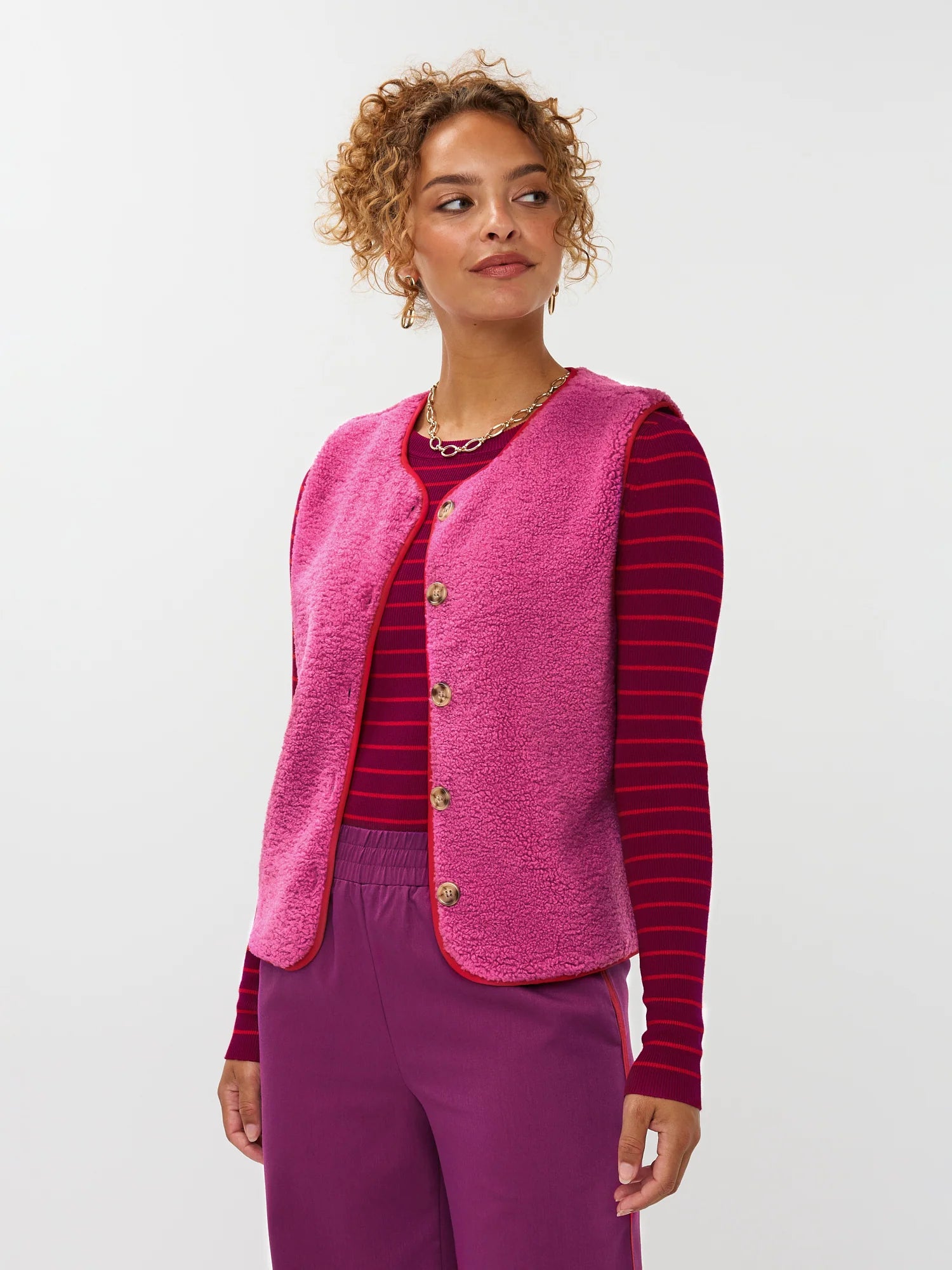 Model draagt het puck gilet van ydende van teddy stof in de kleur fuchsia over de knitted top devina.