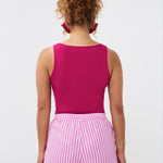 Model draagt de Ydence top Leny in felroze zomerse stijl met een roze-wit gestreepte short, achteraanzicht.