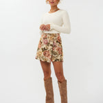 Model draagt de violette skort van ydencemet bloemenprint  onder een witte top.